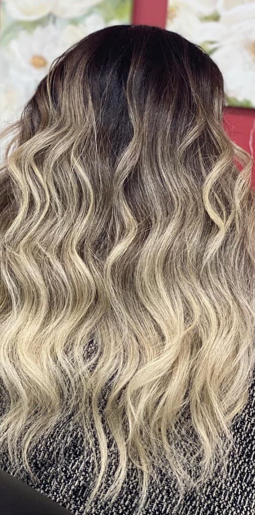 Warm balayage color melt with loose curls back view at R&M Salon